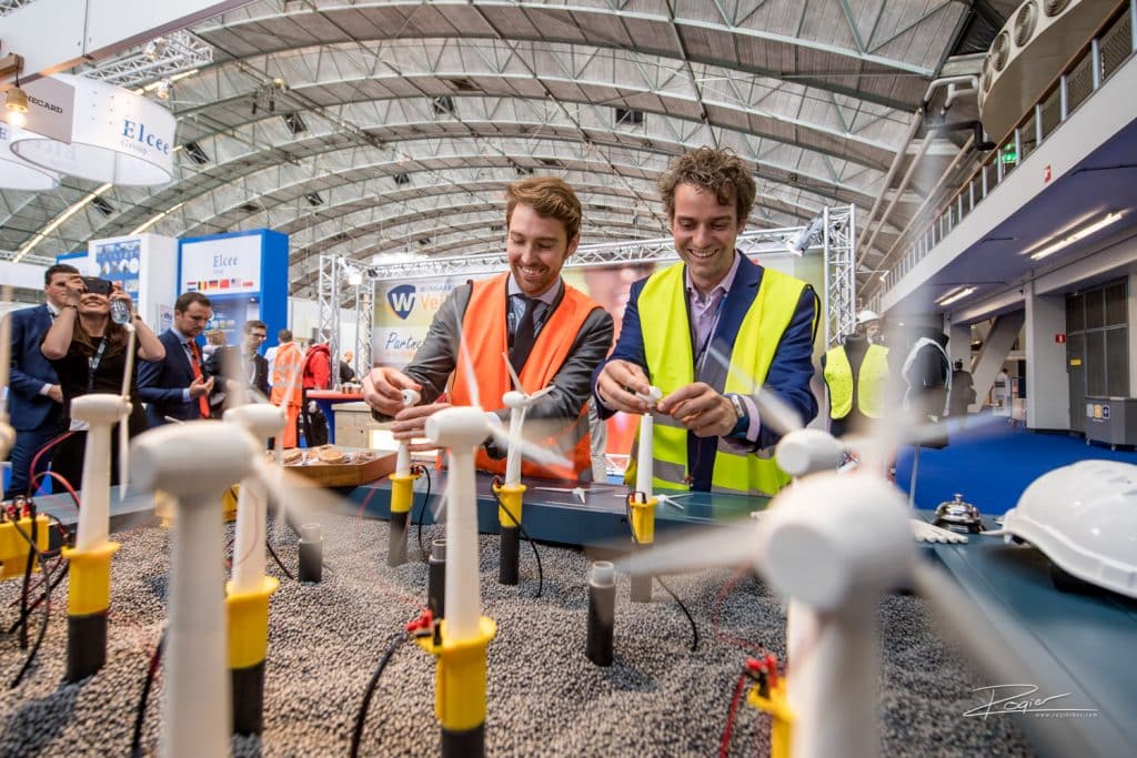 A good example of a picture that I just stumbled upon. This picture says it all: it shows the location (the arches of the RAI); it shows happy people (in suits and yet industrial); in the back ground you the exhibition going on; and in the foreground you see the subject matter of the trade show: windmills producing offshore energy. 