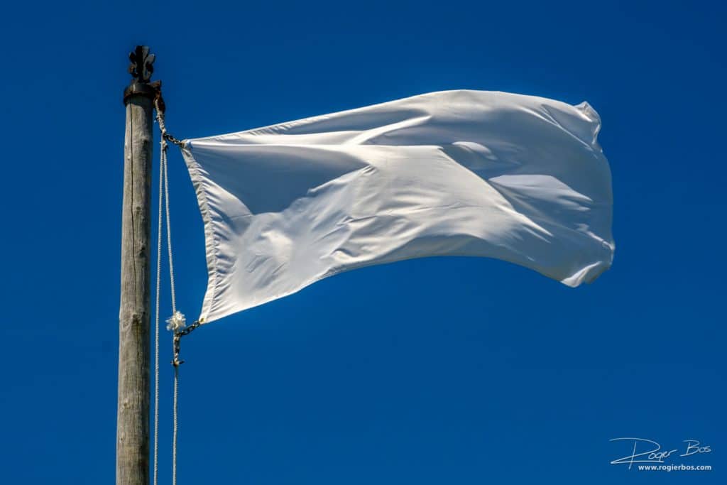 Foto van een witte vlag tegen een blauwe lucht