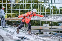 Bouwvakker begeleidt een breedplaat naar zijn plaats in een bouwproject