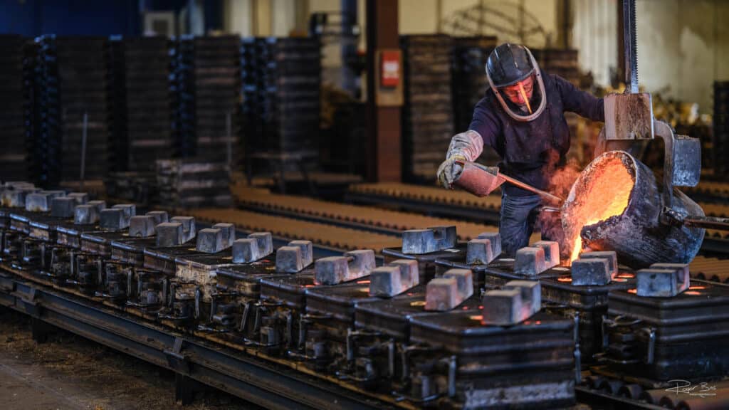 Fotogroafie in staalfabriek — medewerker giet vloeibaar staal