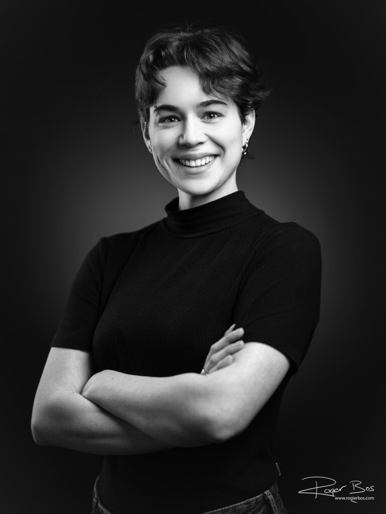 Zwartwit portret van een leuke jonge vrouw vol zelfvertrouwen in de studio.