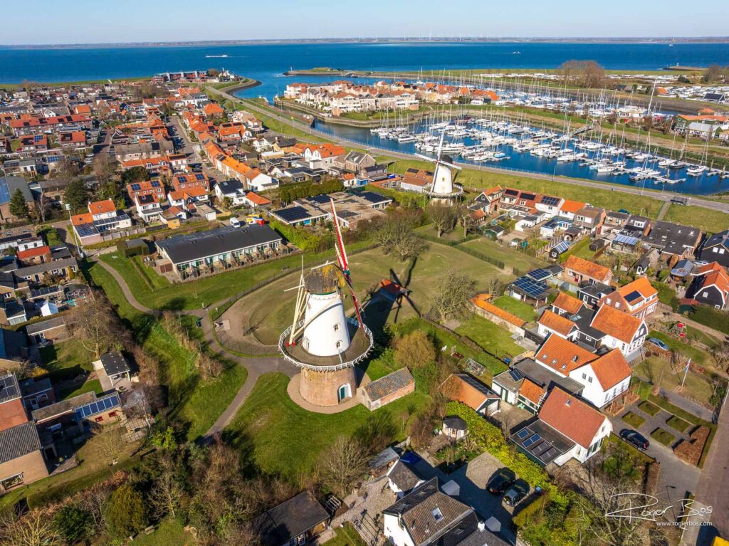 Dronefoto van Kapelle in Zeeland met twee molens, een jachthaven en uitzicht op de kustlijn