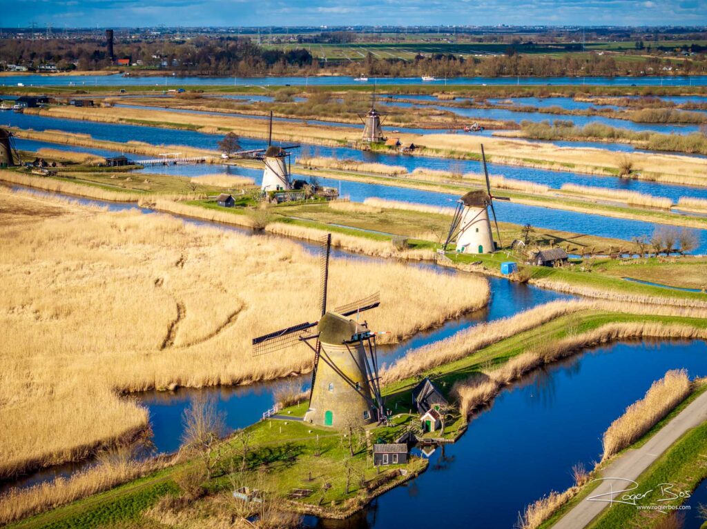 Dronefoto van Kinderdijk met zonovergoten molens omringd door sloten, vaarten en het typisch Nederlandse waterlandschap