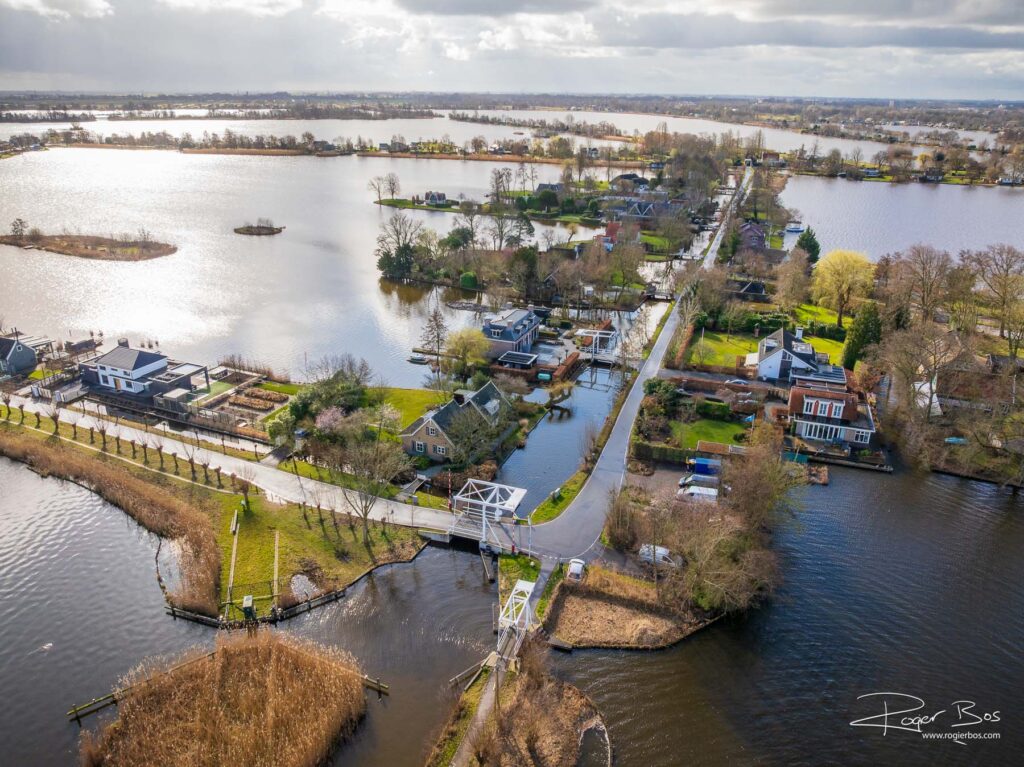 Dronefoto van de Reeuwijkse Plassen met luxe woningen, eilandjes en karakteristieke ophaalbruggen in waterrijk landschap