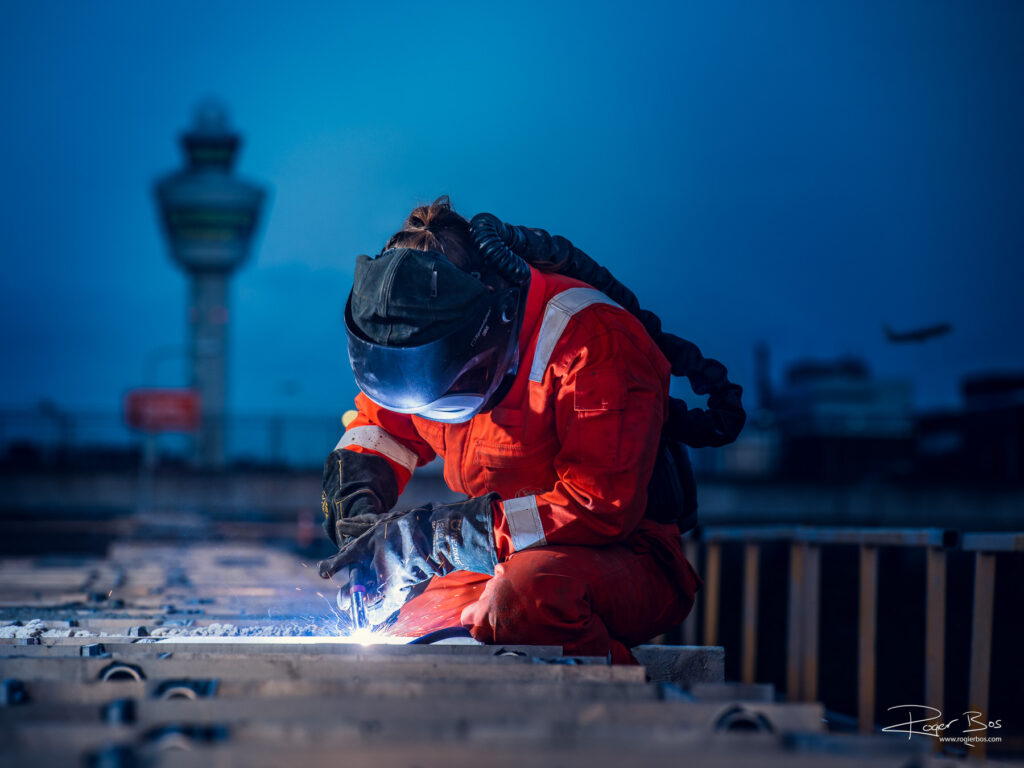 Industriële fotograaf legt lasser vast die ’s avonds werkt aan staalconstructie op Schiphol.