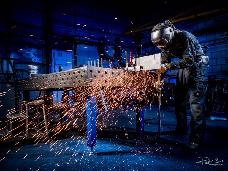 Industriële fotograaf legt metaalbewerker vast die met snijbrander werkt in staalwerkplaats, gefotografeerd in hoge resolutie.