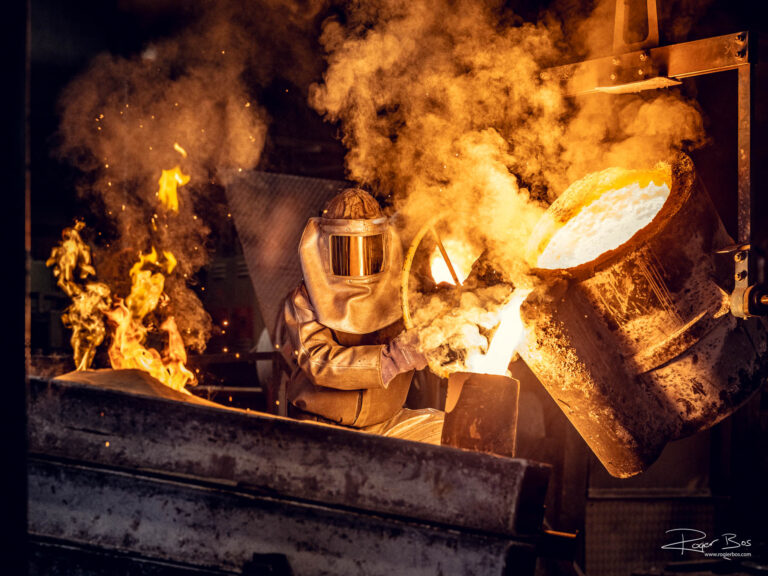 Industriële fotograaf legt smelter vast die vloeibaar metaal giet in gieterij bij hoge temperaturen.