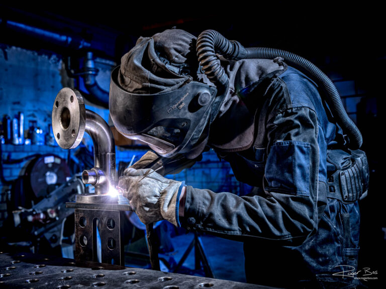 Industriële fotograaf legt lasser vast tijdens TIG-lassen van RVS pijp in werkplaats.