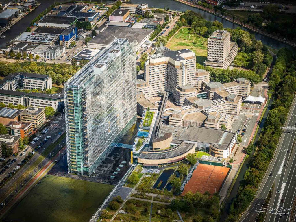 Luchtfoto van het European Patent Office (EPO) in Rijswijk met het kenmerkende glazen hoofdgebouw en omliggende kantoren, vastgelegd door fotograaf Rogier Bos.